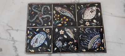 une photo d'un lot de quatre sous-verres en carrelage posés sur une table en marbre