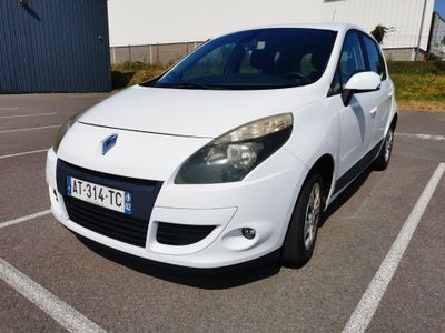 une voiture blanche garée sur un parking devant un immeuble