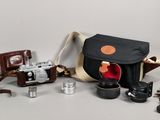 un appareil photo, un étui pour appareil photo, un objectif et d'autres objets posés sur une table