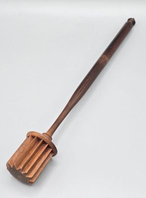 une vieille spatule en bois avec un manche en bois posée sur une surface blanche