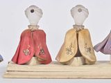 three figurines of people dressed in different colors and patterns