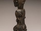 a wooden statue of a woman sitting on a stool