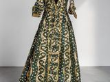 a green and gold silk gown with a v - neckline and long sleeves