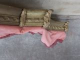 a pink cloth on the floor next to a gold object