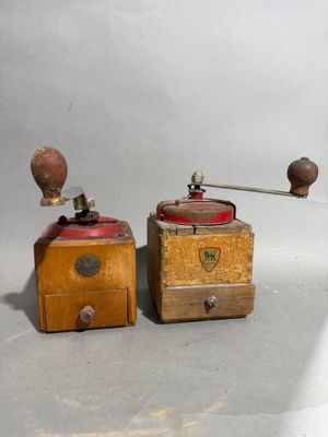 pair of antique coffee grinders with wooden boxes on a white background