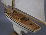 a small model of a sailboat on a wooden stand