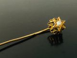a gold pin with a pearl in it on a black surface