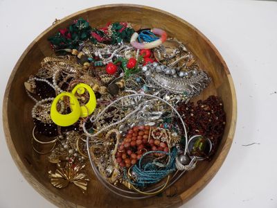 un bol en bois rempli de nombreux bijoux, posé sur une table