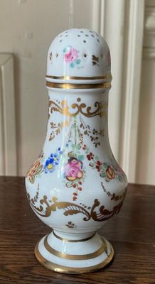 a white vase on a table with gold trimming