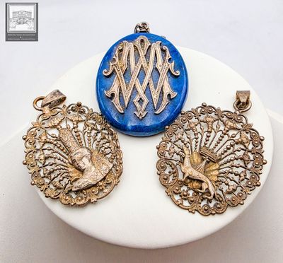 trois pendentifs dorés et bleus posés sur une assiette blanche posée sur une table