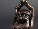 une statue en bronze représentant un homme souriant tenant une pomme de pin