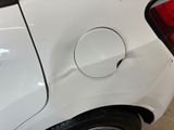 the rear end of a white car with a hole in the side of it