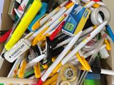 a cardboard box full of pens and other office supplies