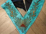 un gros plan sur un collier bleu et or posé sur un parquet