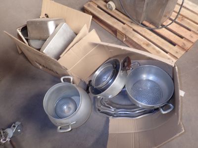 de nombreuses casseroles et poêles dans une boîte posée par terre