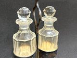 pair of antique glass decanters with metal handles on a black background