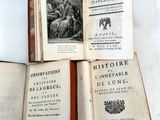 trois livres ouverts posés les uns sur les autres sur une table