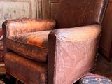 un fauteuil en cuir marron posé sur un tapis dans un salon