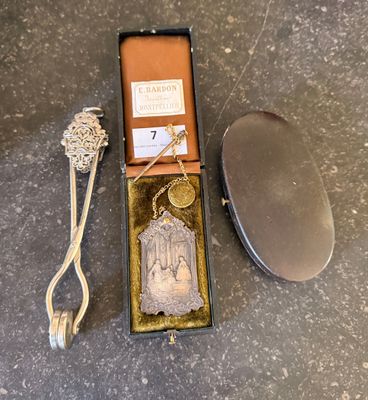 a small metal object in a box next to a pair of scissors