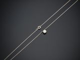 un collier en argent orné d'une perle et d'une chaîne, sur fond noir