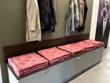 une photo d'un couloir avec un banc et un porte-manteau