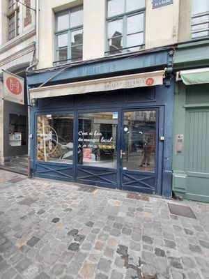 un immeuble bleu avec une vitrine donnant sur une rue pavée
