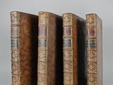 three old books are lined up in a row on a white surface