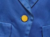 a close up of a blue jacket with a yellow button