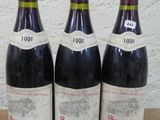 trois bouteilles de vin sont alignées sur une table en bois