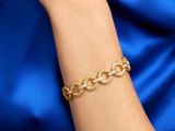 a close up of a woman ' s arm wearing a gold chain bracelet