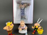 trois figurines représentant des personnages de dessins animés, dans une boîte posée sur une table