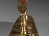 a brass stamper with a wooden handle on a white surface