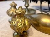 brass figurines of birds on a table with a gold spoon and spoon rest