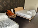 two beds in a small room with a chair and a lamp