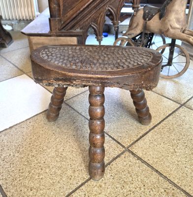une petite table en bois au plateau sculpté, posée sur un sol carrelé
