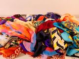 un tas d'écharpes de toutes sortes posées sur un canapé blanc