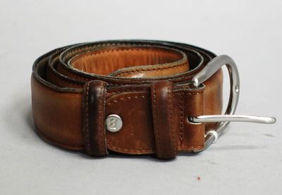 ceinture en cuir marron avec une boucle argentée sur un fond blanc