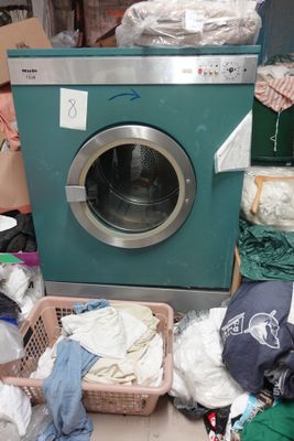 une machine à laver posée par terre à côté d'une pile de vêtements