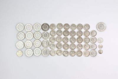 Plusieurs types de pièces de monnaie sont disposés en rangée sur une surface blanche