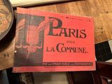 un livre rouge posé sur une table, avec une horloge en arrière-plan
