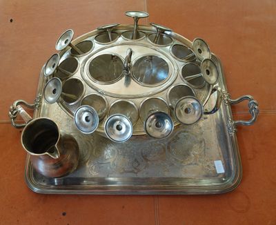 un plateau en argent sur lequel sont posées des tasses et des soucoupes, posé sur un sol carrelé