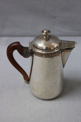 an antique silver coffee pot with a wooden handle on a white surface