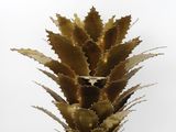 a close up of a metal pineapple on a white surface