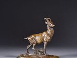 sculpture en bronze représentant un bélier debout sur un rocher, posée sur un socle gris
