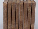 six vieux livres empilés sur une surface blanche