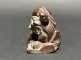 a close up of a figurine of a person sitting on a rock