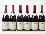 six bouteilles de vin sont alignées sur une surface blanche