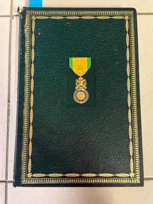 un livre vert sur lequel est posée une médaille d'or
