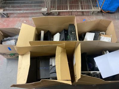 Des cartons contenant du matériel électronique sont empilés les uns sur les autres dans un entrepôt