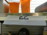 three cups of orange juice on a shelf in a store